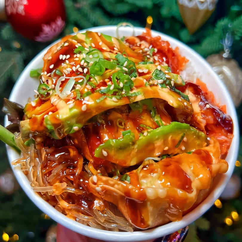 BOPJO Korean-Mexican Grill's colorful bowl with avocado, noodles, and dumplings, garnished with sesame seeds and scallions.