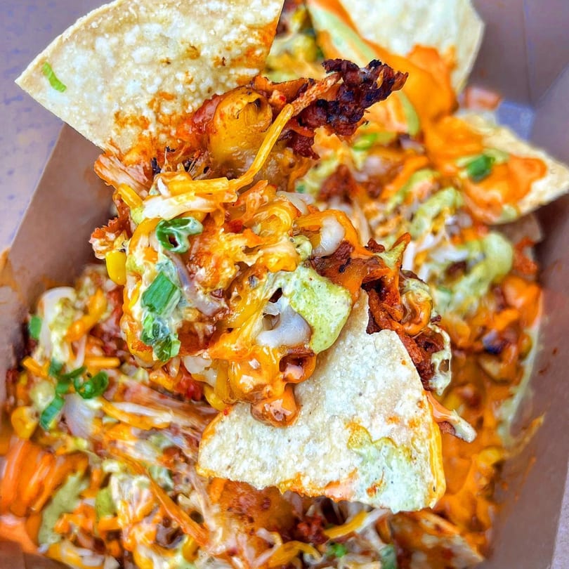 Close-up of BOPJO Korean-Mexican Grill's loaded nachos with melted cheese, meat, and green onions.